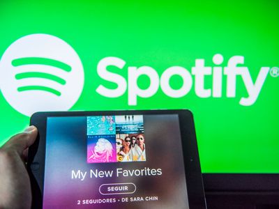 Young man holds a smart device while using Spotify app