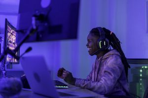 A woman wearing headphones and smiling at her gaming PC.