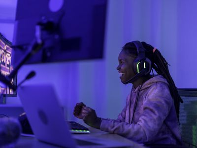 A woman wearing headphones and smiling at her gaming PC.