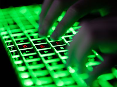 Fingers typing on a backlit green computer keyboard