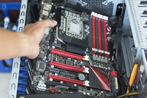 Holding a motherboard in an open computer case.