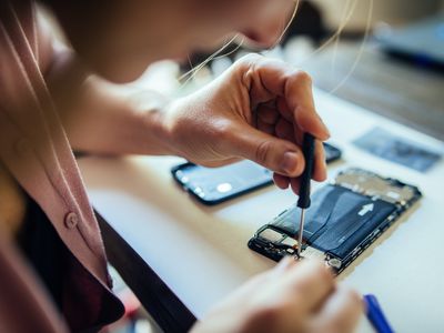 A woman repairing a disassembled smartphone 