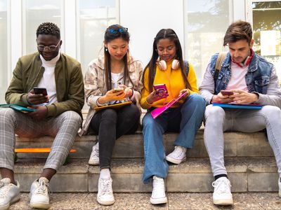 A group of people sitting and playing games on their phones.