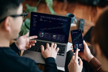 Business people looking at financial data on a laptop and smartphone using AI.