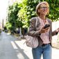 A woman walking down a street, talking on a phone call with wireless headphones