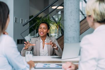 A business person talking to a group of others during a meeting.