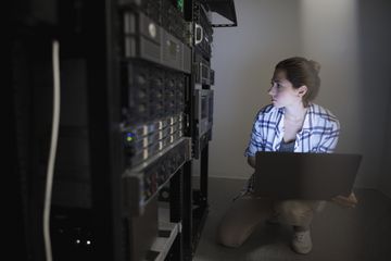 Young network administrator looks at a server rack