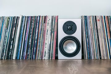 Vinyl records and loudspeaker box on hardwood floor