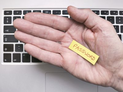 Hand holding note saying Password with keyboard on the background