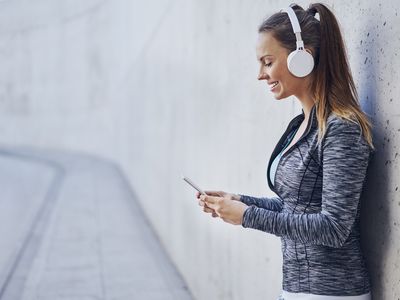 An athlete holding a phone wearing a Bluetooth wireless headphones