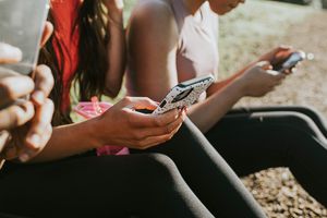 Three teenagers holding smartphones with phone cases on them.