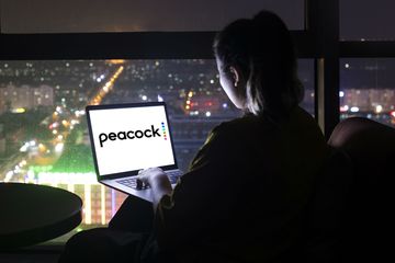 A hotel guest streams Peacock on a laptop.