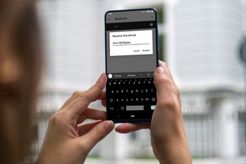 Woman holding Android phone with rename this device prompt on screen