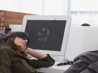 A woman sleeping at her desk because her computer is slow.