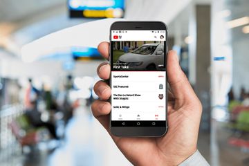 Hand holding phone in train station with YouTube TV on the screen